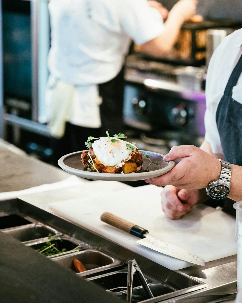 A chef plating a dish in a professional restaurant kitchen